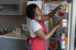 © Anna Berkut/Stocksy - woman taking food in refrigerator in kitchen, open fridge