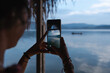 © Luis Herrera/Stocksy - woman taking a photo at a lake