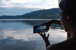 © Luis Herrera/Stocksy - woman taking a photo at a lake