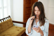 © Artem Zhushman/Stocksy - Woman Looks at Her Phone Screen  While Brushing Teeth