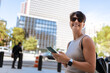 © Alvaro Lavin/Stocksy - Smiling tourist using smartphone in Manhattan, New York City