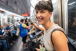 © Alvaro Lavin/Stocksy - Young woman is smiling while commuting by subway in Manhattan