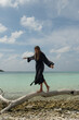 © Alina Hvostikova/Stocksy - Woman balancing on a log by the serene turquoise sea