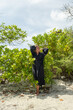 © Alina Hvostikova/Stocksy - Woman enjoying a serene moment amidst lush greenery on the beach
