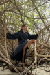 © Alina Hvostikova/Stocksy - Woman poses gracefully among tangled branches by the shore
