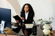 © Sergey Narevskih/Stocksy - Professional woman looking at notebook at desk in office