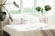 © Pixel-Shot - Interior of light bedroom with cozy bed and monstera leaves