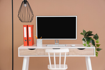Wall Mural - stylish table with computer, houseplant and folders on beige background