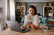 © Mihajlo Ckovric/Stocksy - Young Woman Shopping Online Using Laptop and Credit Card