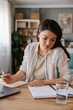 © Mihajlo Ckovric/Stocksy - Focused Woman Writing Notes While Working on a Laptop at Home