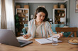 © Mihajlo Ckovric/Stocksy - Focused Woman Writing Notes While Working on a Laptop at Home