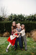 © Melissa Milis Photography/Stocksy - Boy getting cuddles by girl friends on Christmas day in the garden