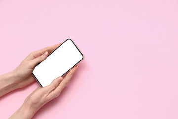 Wall Mural - female hands with mobile phone on pink background