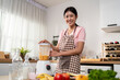 © Kawee - Portrait of woman making fruit smoothies in blender in kitchen at home.