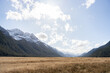 © David Keller/Stocksy - Dry grassland surrounded by snowy mountain peaks