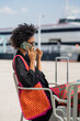 © tessy morelli/Stocksy - Lisbon woman at cafe by the river on phone call