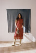 © Tania Cervian/Stocksy - Film photography of woman in red dress with bag in room