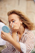 © Boris Jovanovic/Stocksy - Woman applies mascara outdoors