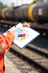 Wall Mural - action of an engineer is checking on the chemical hazard material form with background of crude oil 