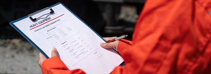 Wall Mural - an engineer is checking heavy machine checklist form during inspecting condition, with blurred backg