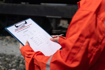 Wall Mural - an engineer is checking heavy machine checklist form during inspecting condition, with blurred backg