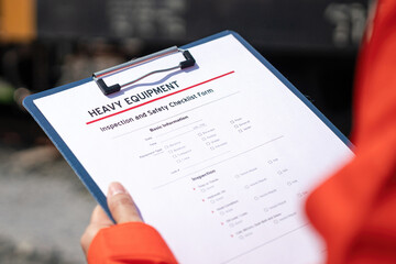 Wall Mural - an engineer is checking heavy machine checklist form during inspecting condition, with blurred backg