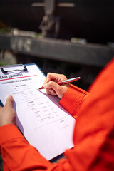 Wall Mural - an engineer is checking heavy machine checklist form during inspecting condition, with blurred backg