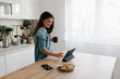 © Mihajlo Ckovric/Stocksy - Woman Enjoying Coffee While Browsing on a Tablet in Modern Kitchen