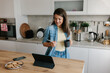 © Mihajlo Ckovric/Stocksy - Smiling Woman Enjoying Coffee While Watching Tablet in Modern Kitchen