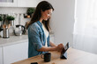 © Mihajlo Ckovric/Stocksy - Young Woman Using Tablet in Modern Kitchen While Relaxing With Coffee
