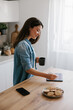 © Mihajlo Ckovric/Stocksy - Young Woman Using Tablet in Modern Kitchen While Relaxing With Coffee