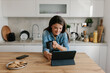 © Mihajlo Ckovric/Stocksy - Young Woman Using Tablet While Enjoying Coffee in a Modern Kitchen
