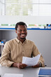© Jovo Jovanovic/Stocksy - Happy businessman holding papers at the desk