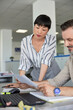 © Jovo Jovanovic/Stocksy - Smiling man explaining colleague over paper and laptop