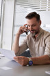 © Jovo Jovanovic/Stocksy - Happy man talking on mobile phone at desk