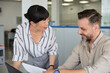 © Jovo Jovanovic/Stocksy - Smiling manager explaining colleague over paper at the desk
