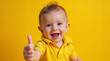 © TimosBlickfang - Cheerful Baby Giving Thumbs Up with a Bright Smile on Yellow Background