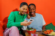 © BONNINSTUDIO/Stocksy - Couple laughing and using smartphone in modern restaurant