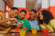 © BONNINSTUDIO/Stocksy - Happy friends sharing funny content on smartphone at restaurant