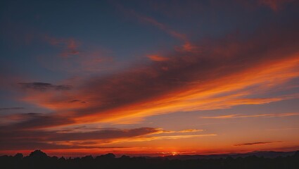 Poster - Vibrant deep orange and blue sunset sky with wispy clouds at dusk featuring a dark silhouette of hills creating ample copyspace for text or design.