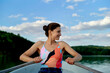 © Connect Images - Woman rowing a boat on a lake under a bright sky with scattered clouds. Brandenburg, Germany