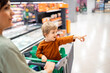 © Santi Nuñez/Stocksy - Boy pointing at something while sitting in shopping cart