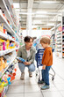 © Santi Nuñez/Stocksy - Mother showing product to her son hoy su buy