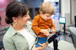 © Santi Nuñez/Stocksy - Mother and son using cellphone to pay at supermarket