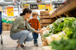 © Santi Nuñez/Stocksy - Mother and son choosing fresh vegetables in supermarket