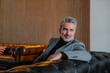© VICTOR TORRES/Stocksy - Thoughtful mature man in stylish suit resting on leather couch