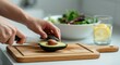 © Tati - Slicing avocado on wooden cutting board in kitchen
