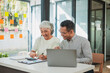 © ArLawKa - Senior Asian business people female and male working with laptop and documents doing financial accounting together using laptop. Training web design in workspace.
