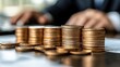 © SiriToshi - Stacks of coins on desk with blurred background of person working