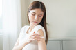 © KMPZZZ - Health skin care, beauty smile asian young woman, girl hand applying, putting moisturizer on her arm, shoulder after shower bath at home. Skin body cream moisturizing lotion, routine in the morning.